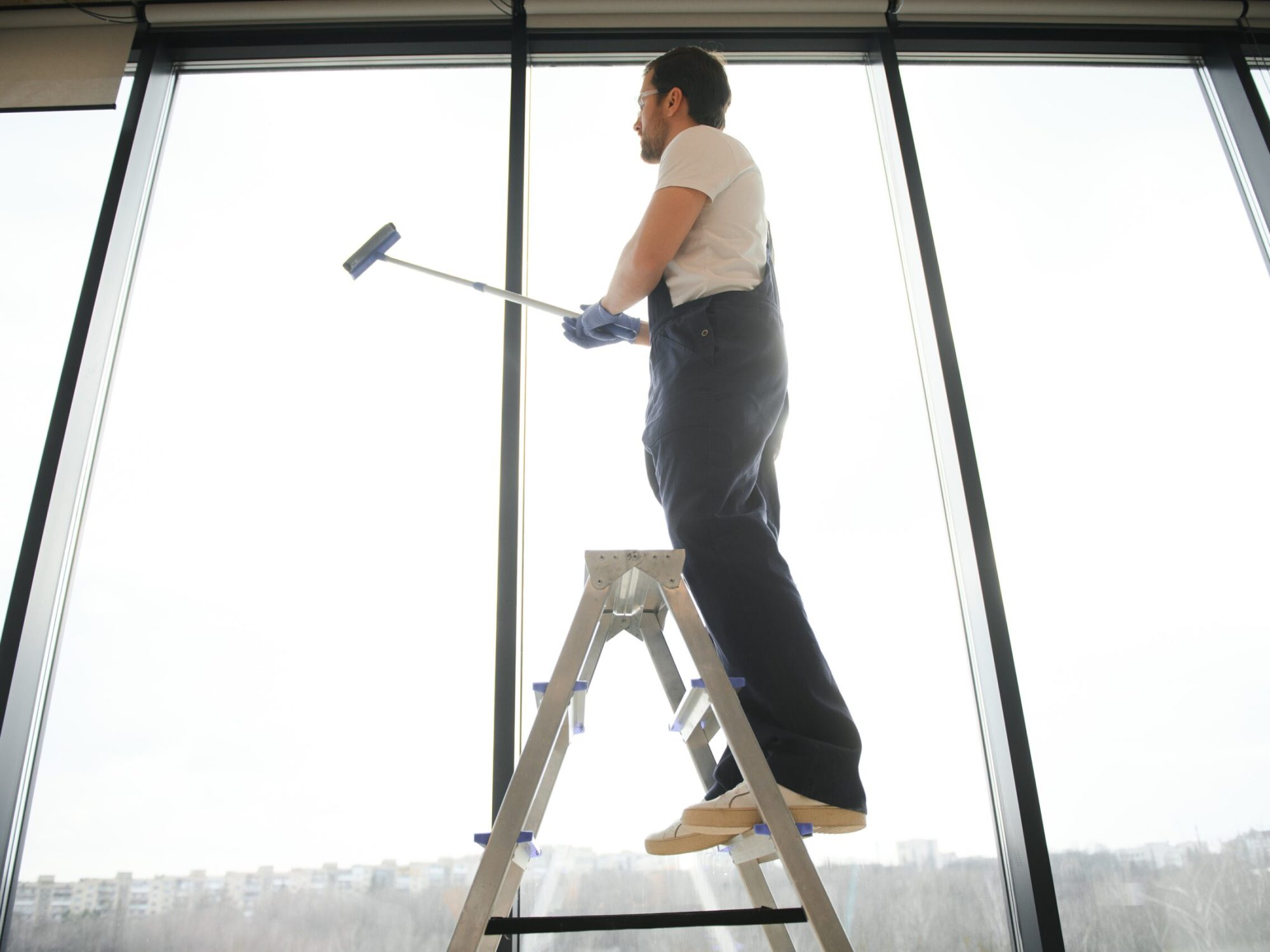 An employee of a professional cleaning service washes the glass of the windows of the building. Showcase cleaning for shops and businesses
